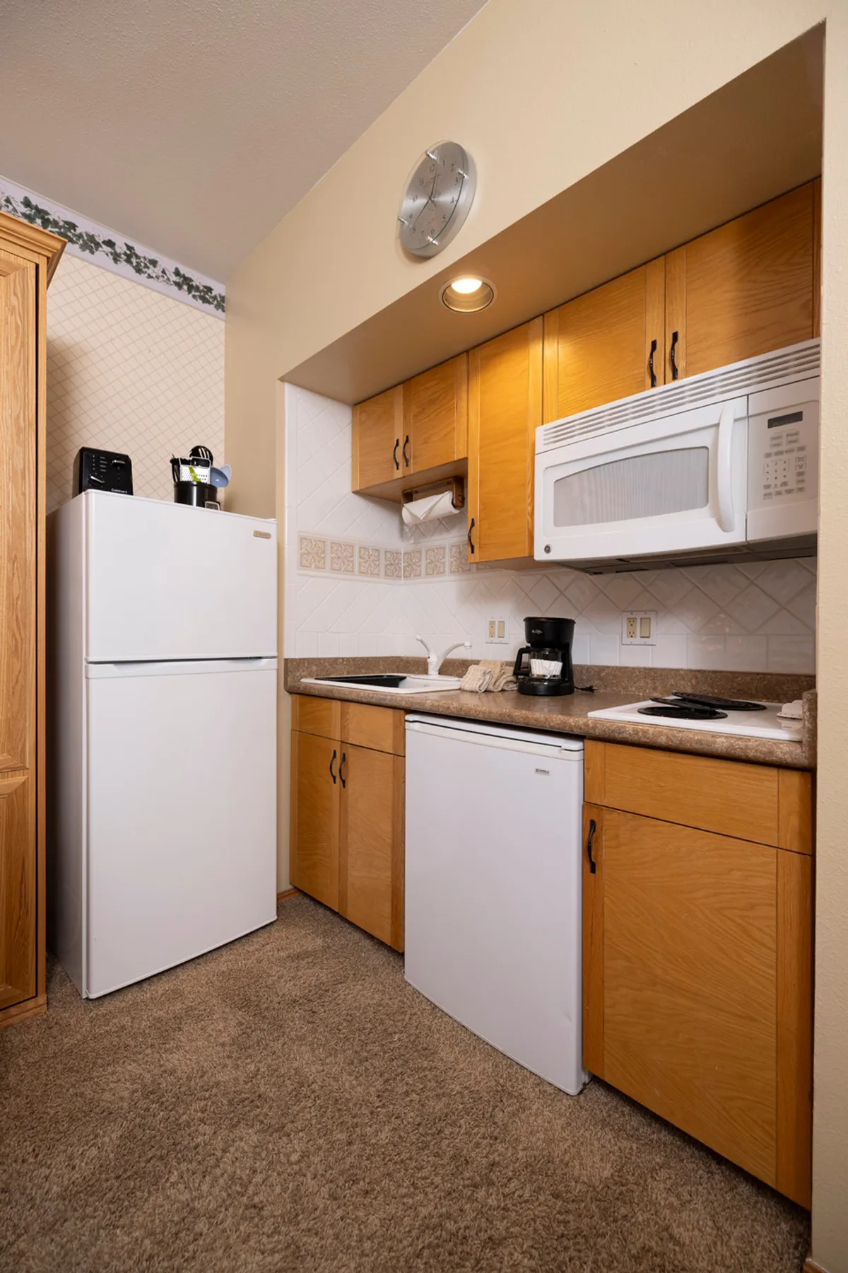 A close-up view of the kitchen area, featuring modern appliances, wooden cabinetry, and a welcoming countertop. The scene is set for meal preparation or enjoying a morning coffee, emphasizing practicality and warmth.